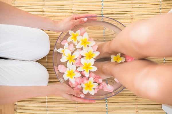 woman washing her feet in a bowl of flower at the spa institute